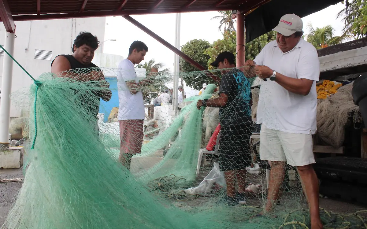 Pescadores reparan sus redes durante el mal tiempo que pasa por el puerto